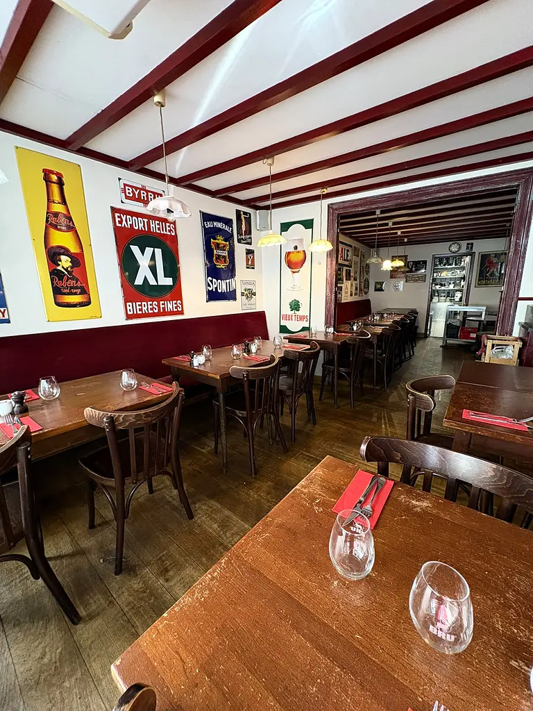 La grande salle des Brassins : plaques émaillées de brasseries belges, banquette bordeaux et tables de chêne.