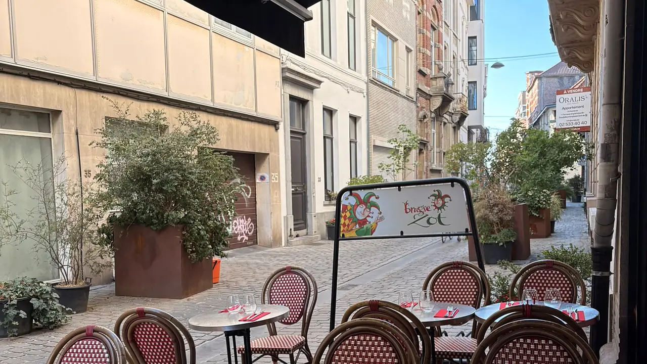 La terrasse des Brassins, chaises en rotin rouge et blanc sur les pavés de la rue Keyenveld.